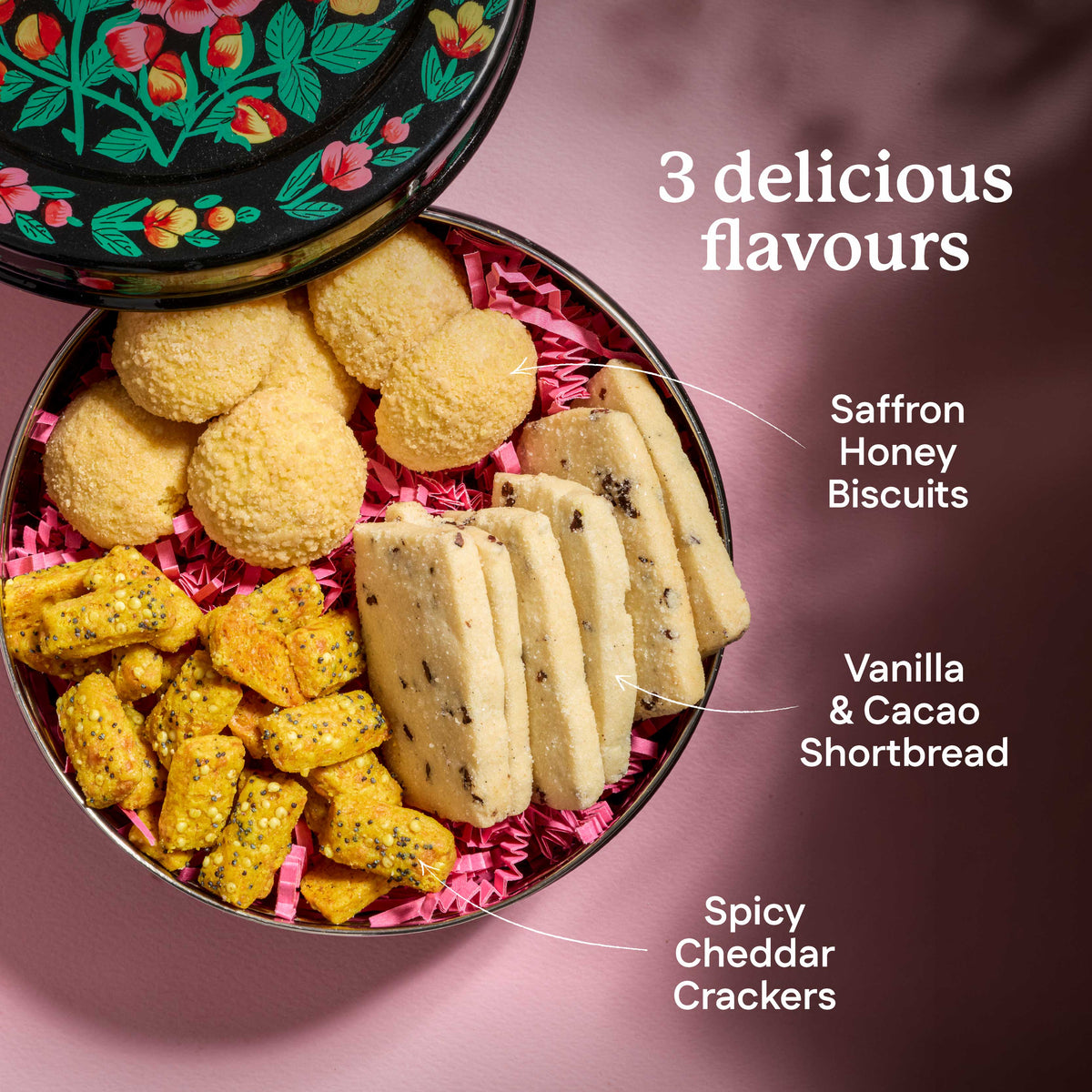 Assorted cookies in a tin with labels for flavors on a pink background